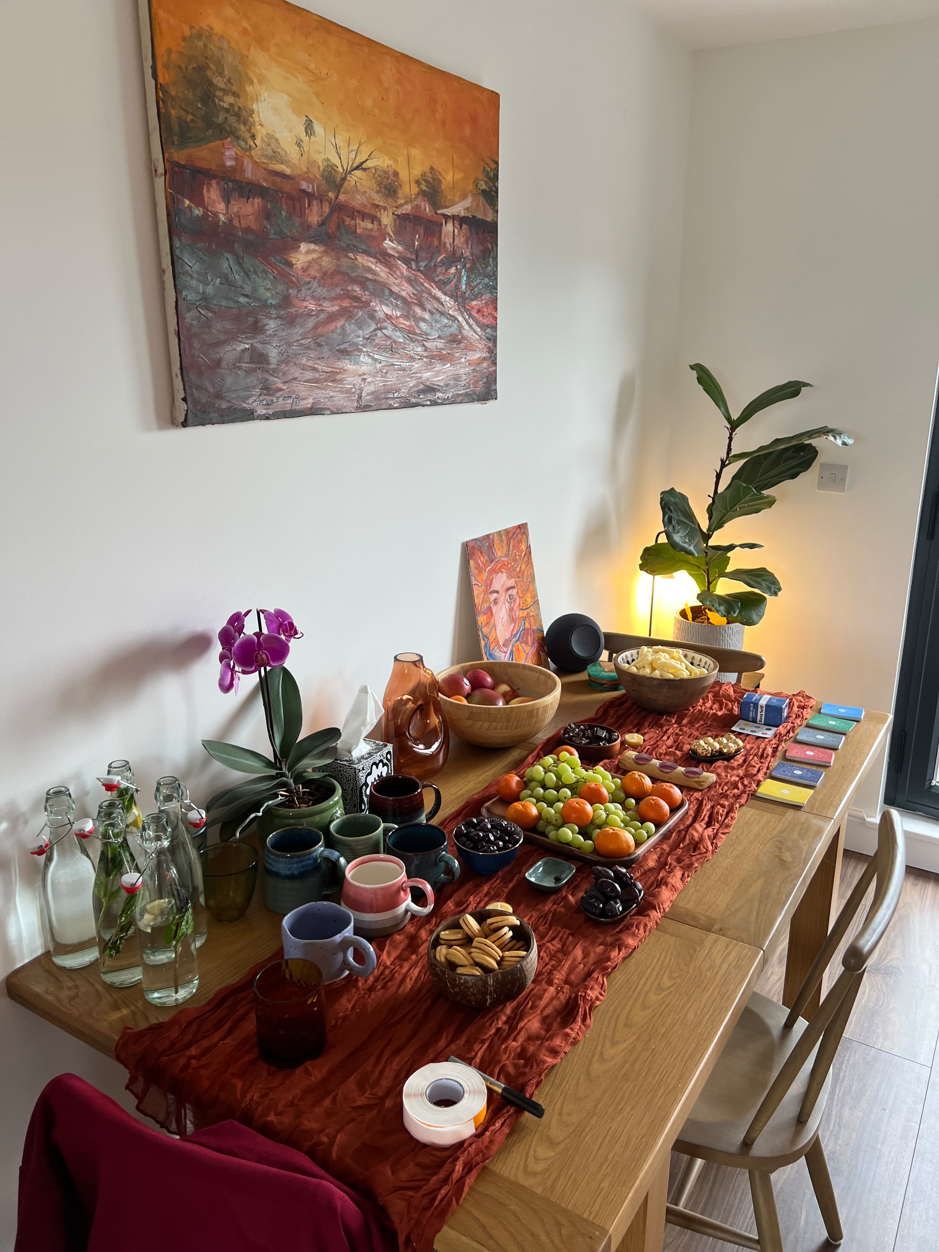 A welcoming studio table arranged with fruit, tea, candles and affirmation cards